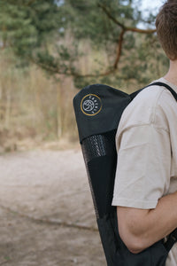 Une personne porte le tapis de yoga Earthle dans sa housse sur le dos, en forêt