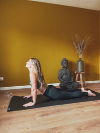 Femme en étirement sur le tapis de yoga Earthle posé sur un parquet