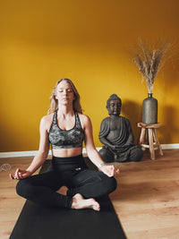 Femme méditant en tailleur sur le tapis de yoga de mise à la terre Earthle