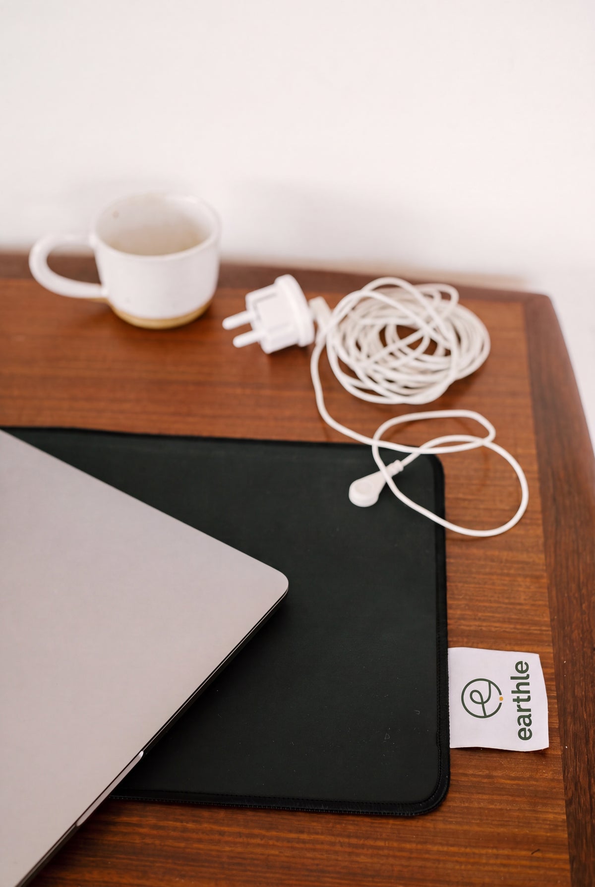 Tapis de bureau de mise à la terre Earthle sur un bureau en bois avec ordinateur portable, tasse de café et le câble enroulé