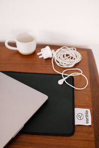 Tapis de bureau de mise à la terre Earthle sur un bureau en bois avec ordinateur portable, tasse de café et le câble enroulé
