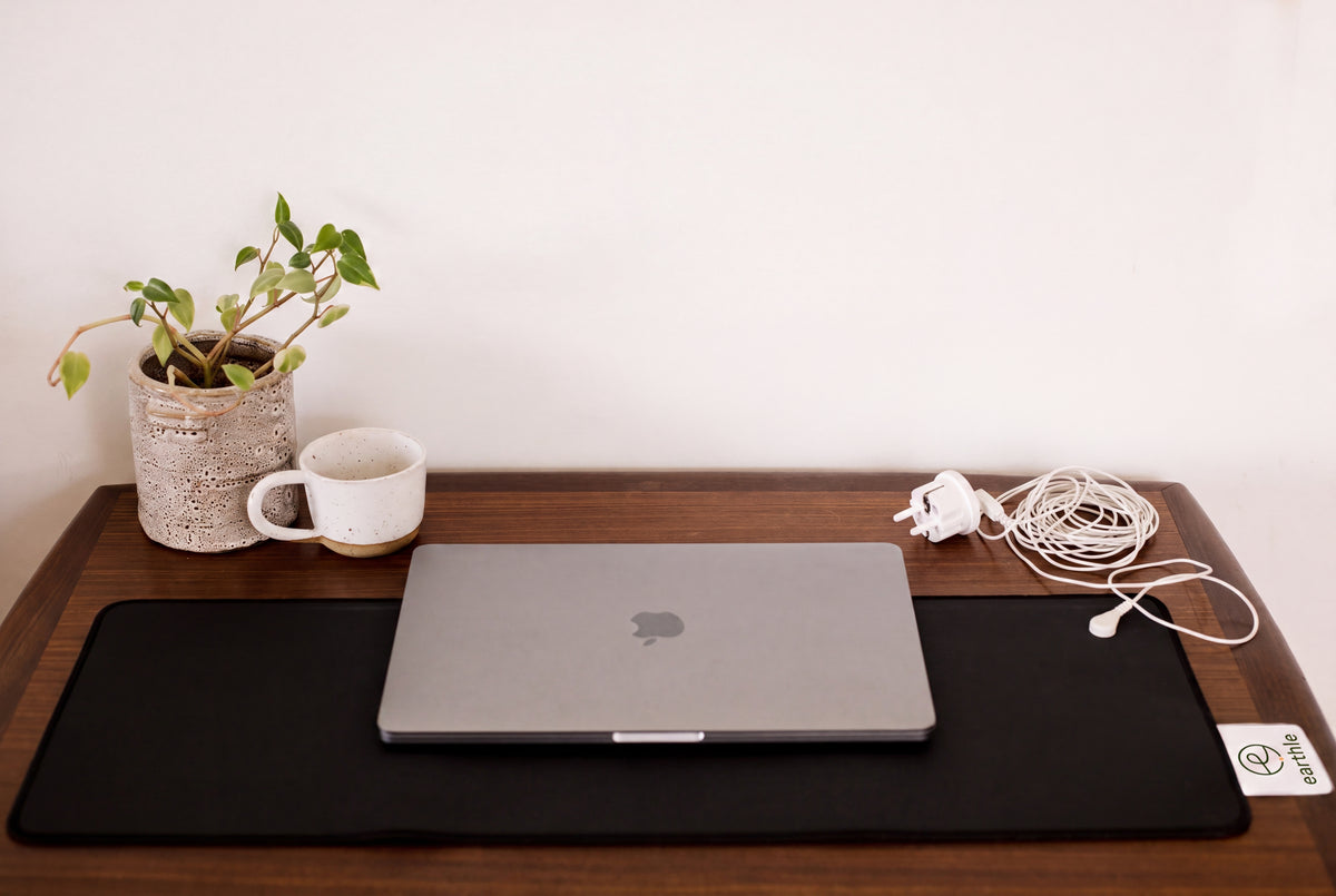 Tapis de bureau de mise à la terre Earthle sur un bureau avec ordinateur portable, plante et tasse, câble vers la prise