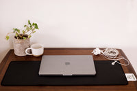 Tapis de bureau de mise à la terre Earthle sur un bureau avec ordinateur portable, plante et tasse, câble vers la prise